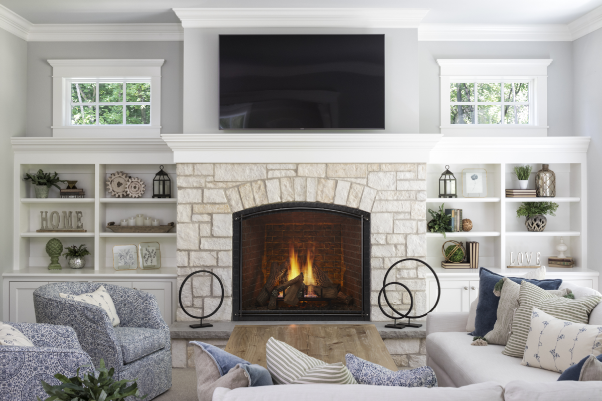 Trendy fireplace with decorative arch and custom cabinets